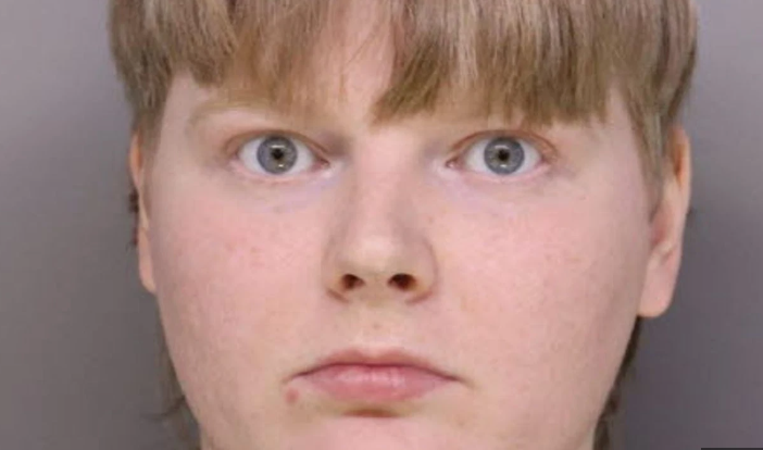 A man in a suit with a thoughtful expression against a bright sky.