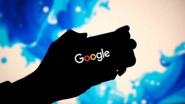 Silhouette holding smartphone with Google logo, vibrant background