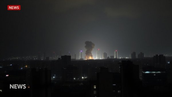 Israel-Iran missile exchange news with city and smoke plume at night.