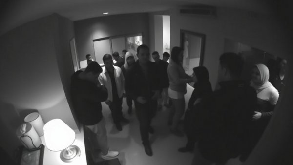 Monochrome surveillance footage of a group in dimly lit room - Houston news shooting.
