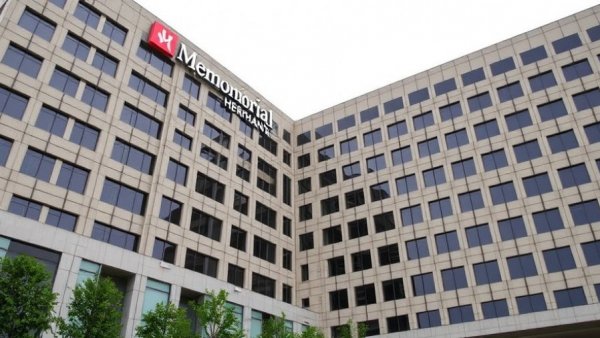 Memorial Hermann hospital building with modern architecture under cloudy sky.