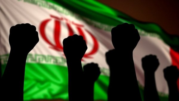 Protest scene with raised fists against Iranian flag backdrop.