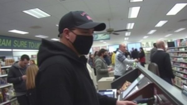 Surveillance image of person at checkout in dark cap, gym locker credit card theft context.