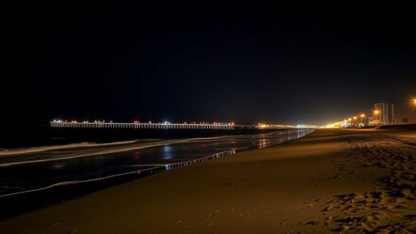 Nighttime view of Surfside Beach with bright lights reflecting off the water.