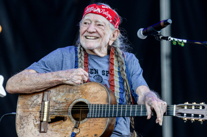 Willie Nelson smiling with guitar on stage, showcasing Austin lifestyle and music legends.