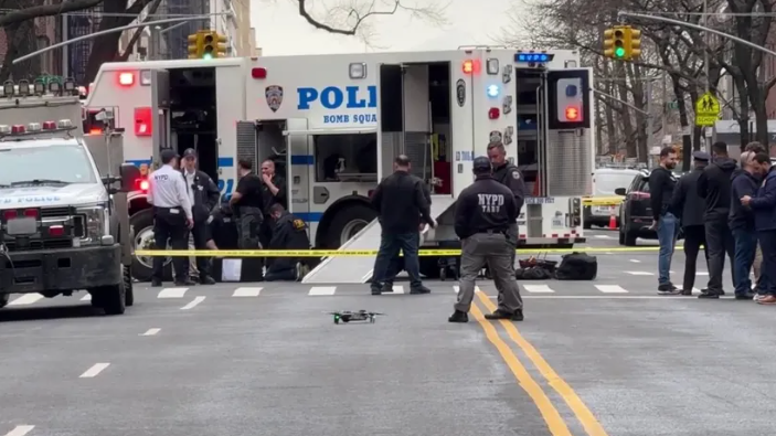 People inspecting suspicious device in urban setting, NYPD IED investigation context.