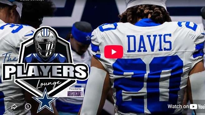 Dallas Cowboys players huddling, missing Malik Davis, under stadium lights.