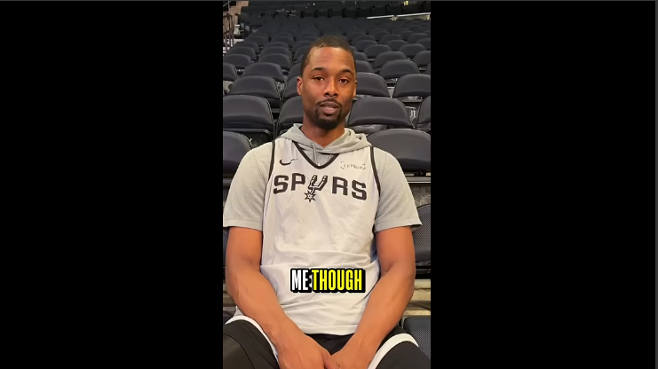 San Antonio Spurs coach with athletes discussing books at an arena.