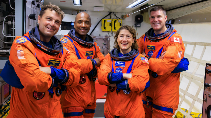 Astronauts smiling in spacecraft for NASA Artemis II wake-up songs concept.