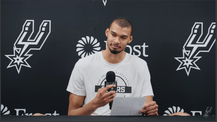 San Antonio Spurs player and interview shot, vibrant indoor scene.