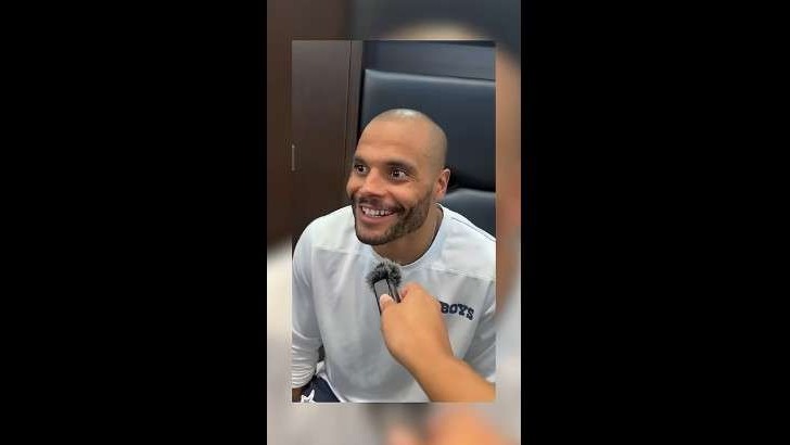 Dallas Cowboys practice visits at indoor setting with man in headphones.