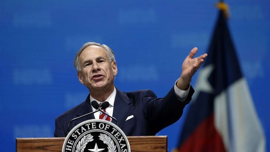 Cheerful man waving at a nighttime crowd amid Texas governor news.