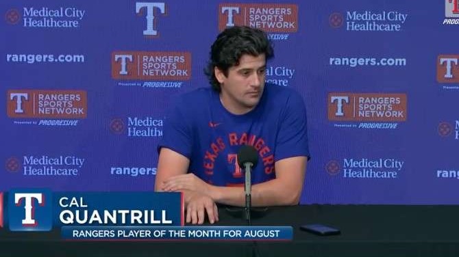 Man speaking at a press conference in a Rangers shirt