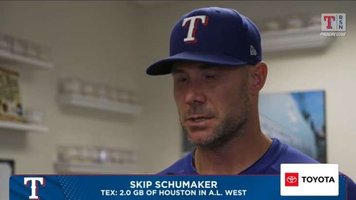 Sports interviewer and baseball coach in locker room discussion.