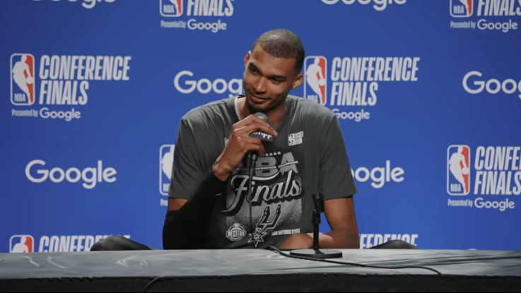 San Antonio sports celebration, basketball player joyfully raising fists.