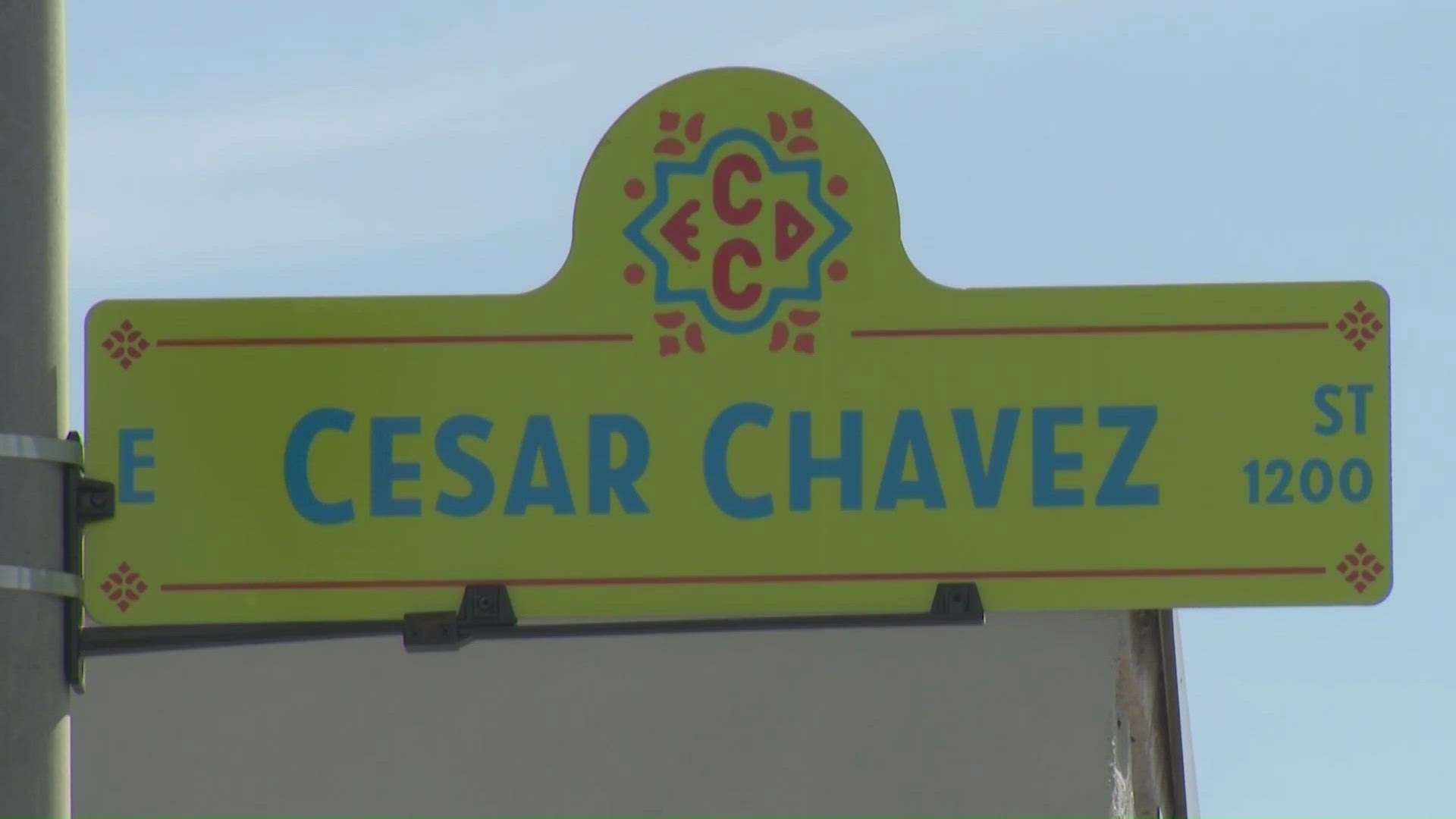 Street sign for W Cesar Chavez beneath traffic light in Austin city.