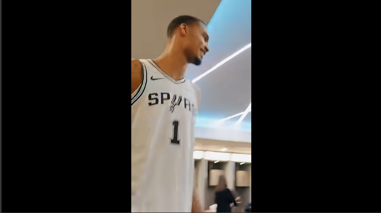 San Antonio Spurs members in casual conversation indoors.