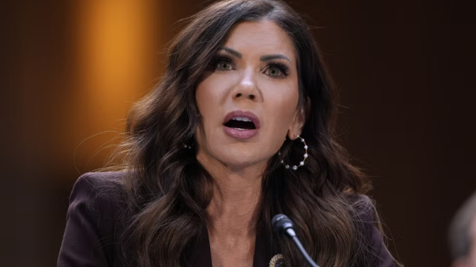 Thoughtful woman at a microphone during a formal meeting, related to Trump cabinet changes.