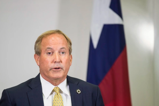 Man in suit at press conference, emblem in background, Dallas city news.