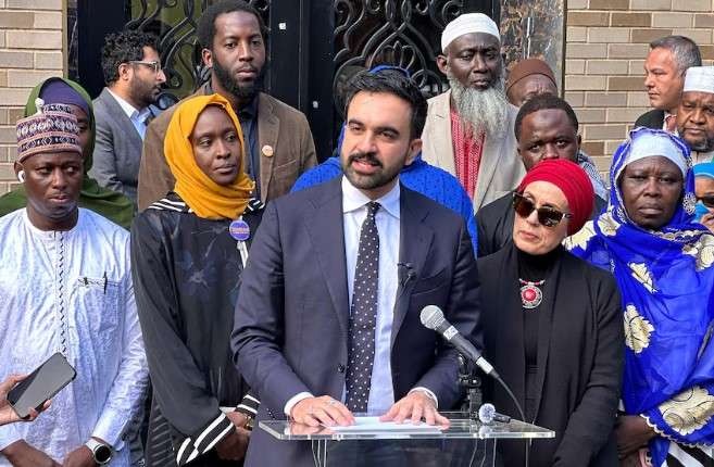 Zohran Mamdani mayor standing confidently with supporters in NYC, capturing political implications.